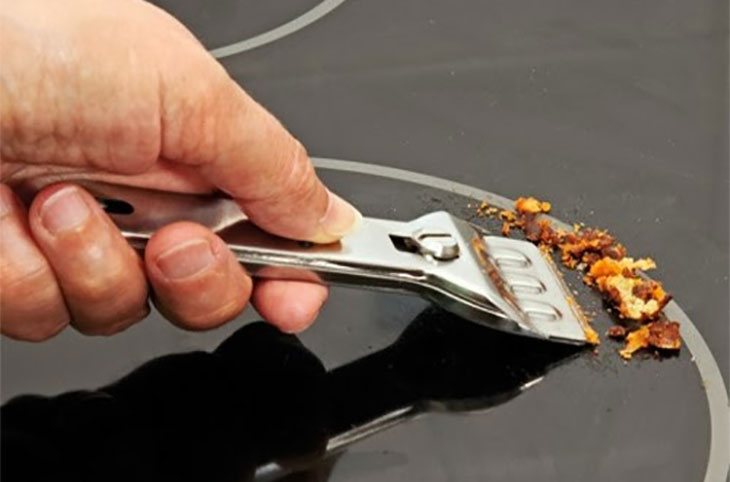 Bạn hãy dùng dao cạo bếp chuyên dụng trên bề mặt kính của bếp hồng ngoại